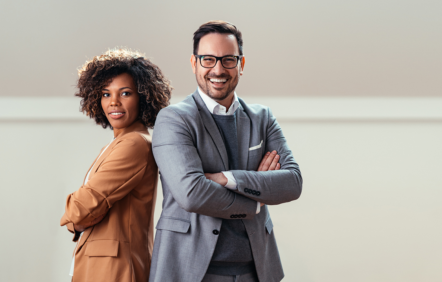 Portrait of happy multi ethnic business couple posing with arms crossed
